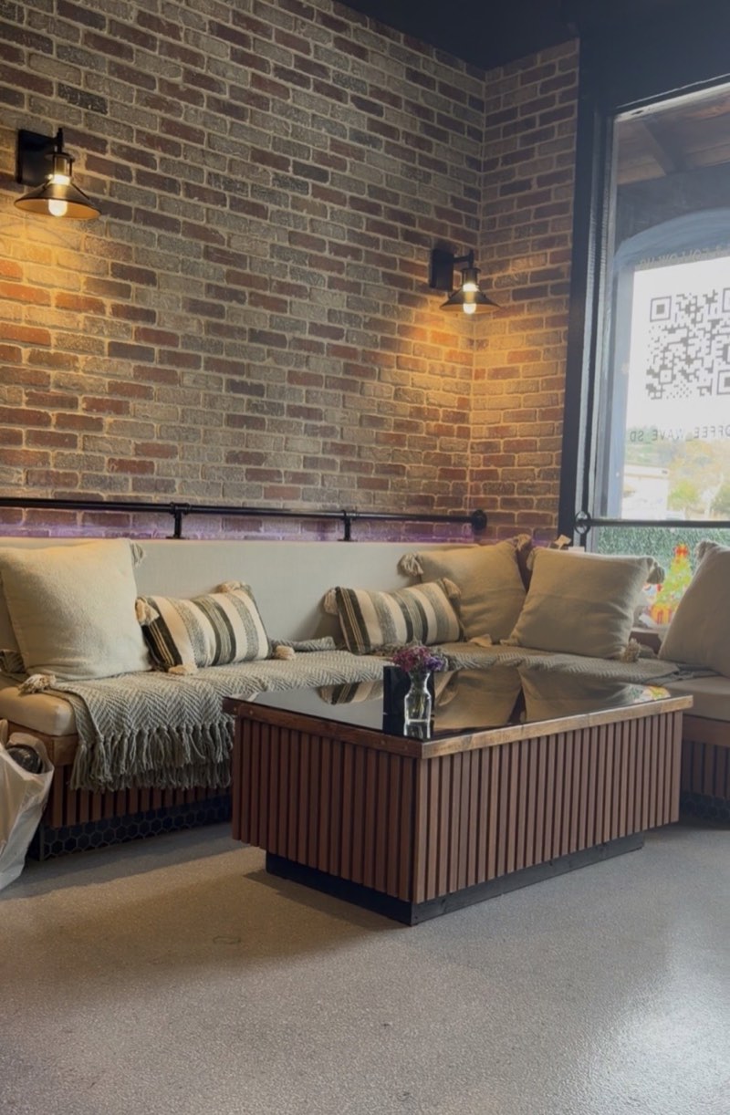 Coffee Wave's cozy lounge with soft seating, brick walls, and warm lights